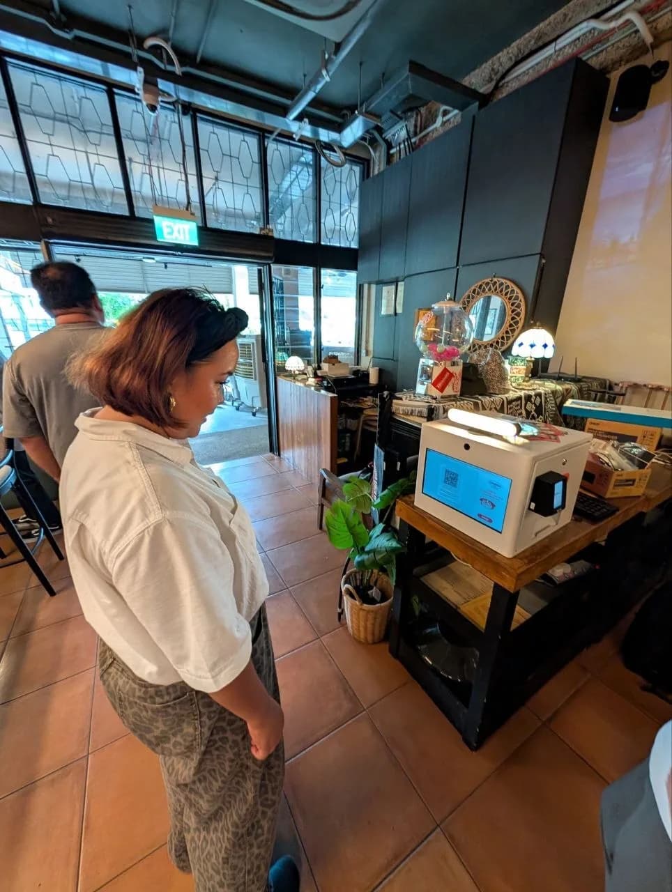 A person looking at Raon mini photo booth machine inside a cafe
