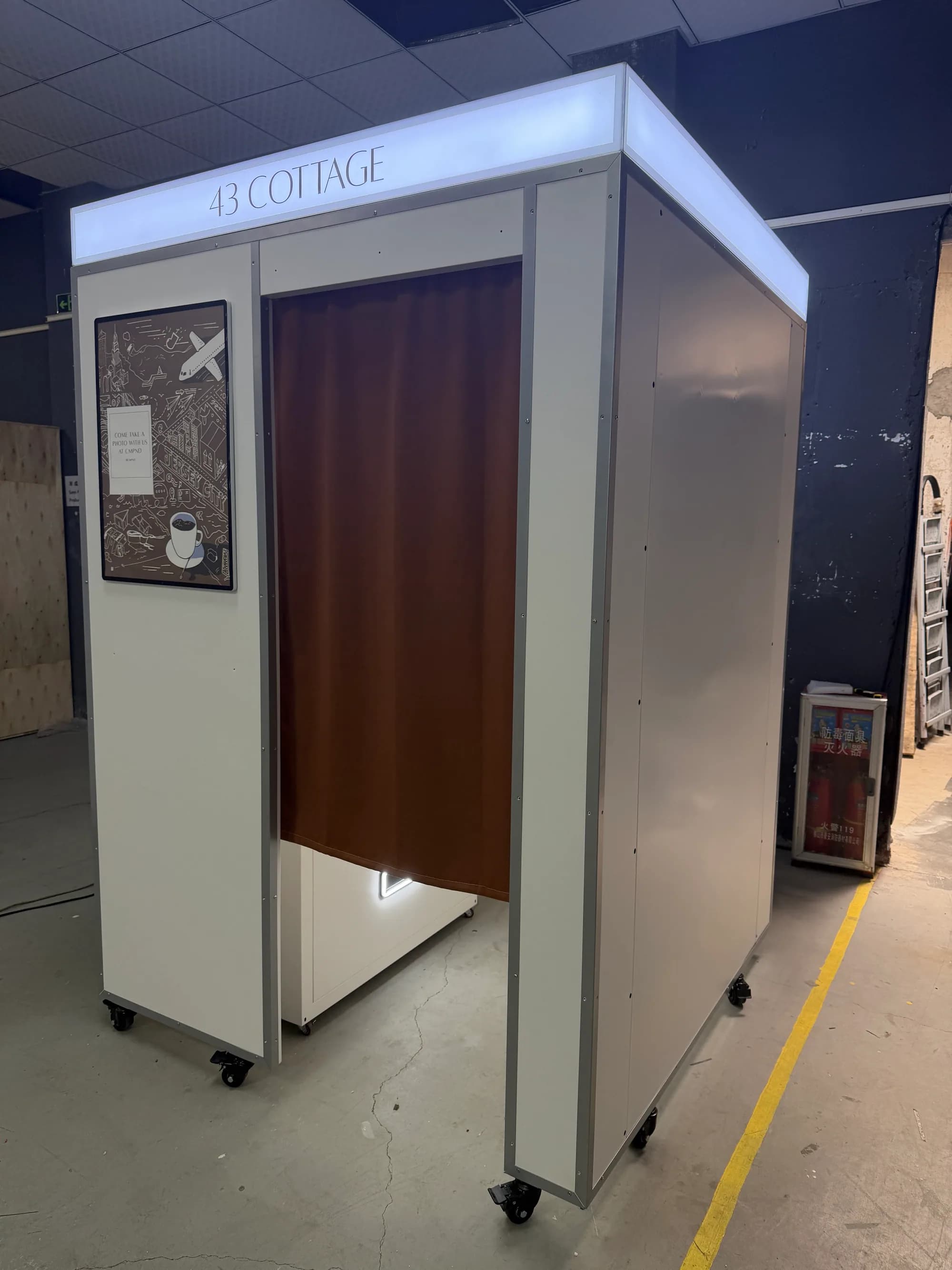 White and grey vintage photo booth with a lit 43 Cottage sign and brown curtain