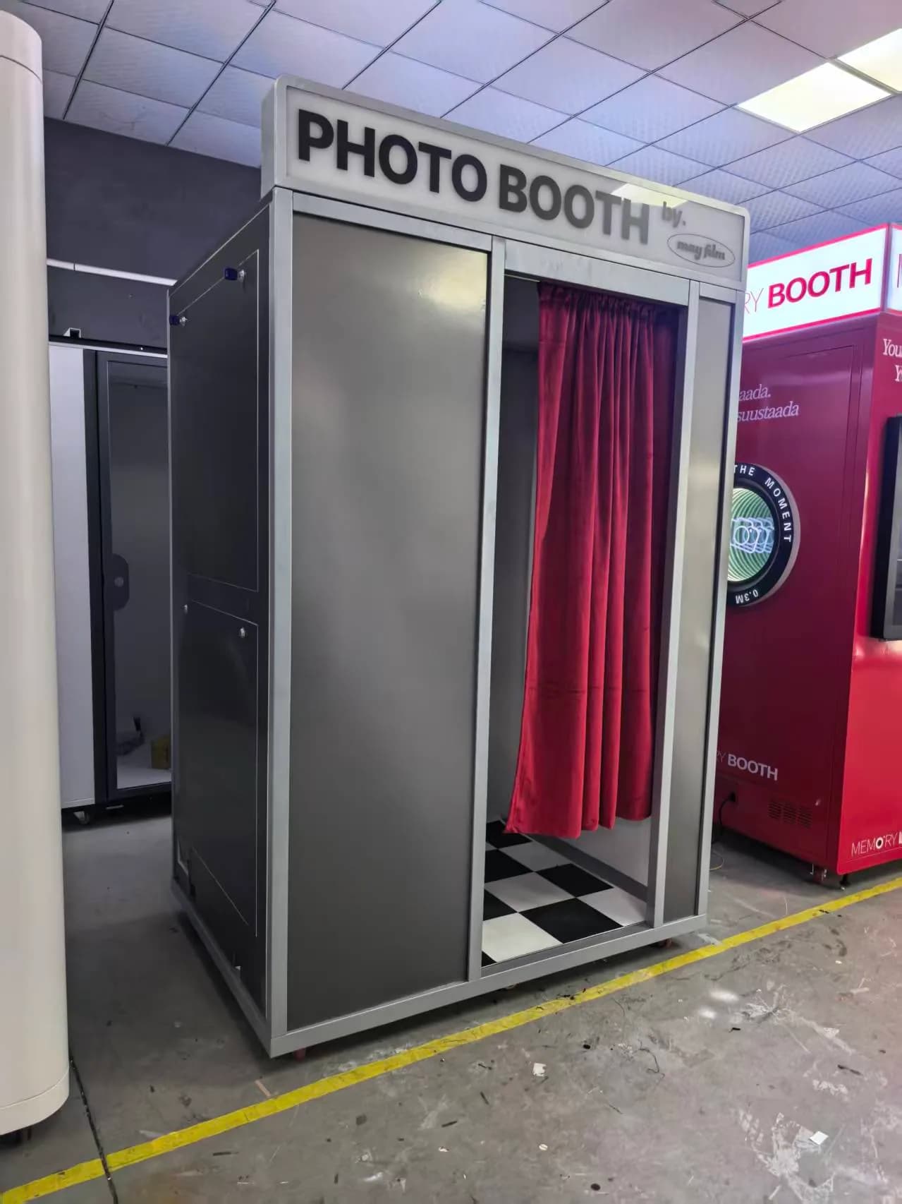 Grey vintage photo booth with a red curtain and checker floor built for May Film