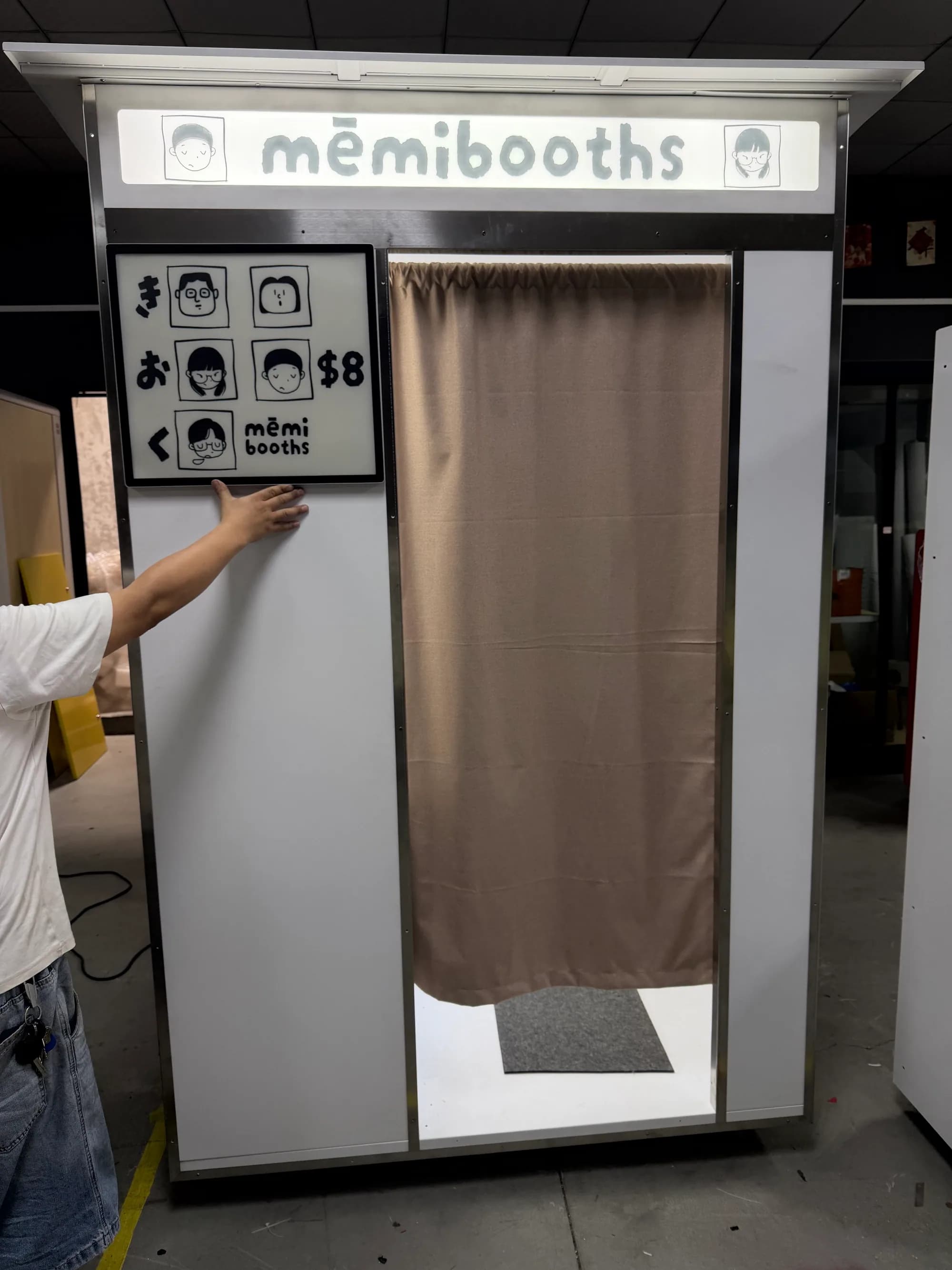 White vintage photo booth with the memi booths sign and a beige curtain