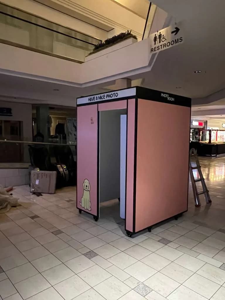Pink vintage photo booth with a black frame placed in a shopping mall