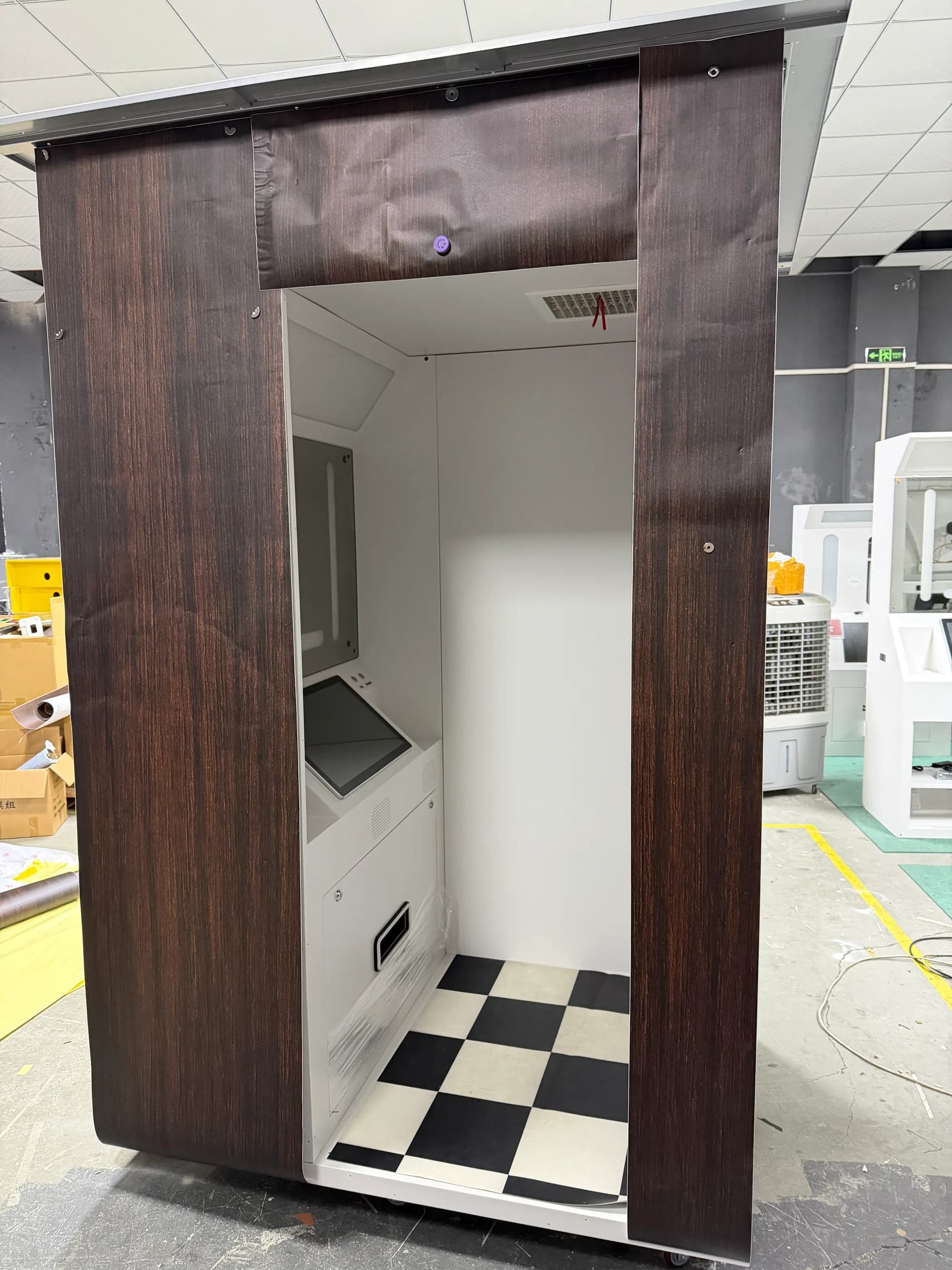 Wood-grain vintage photo booth open at the front showing the machine and checker floor