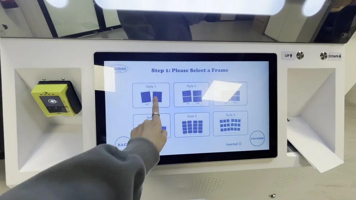 Customer choosing a frame on a photo booth touchscreen, with the card reader beside it