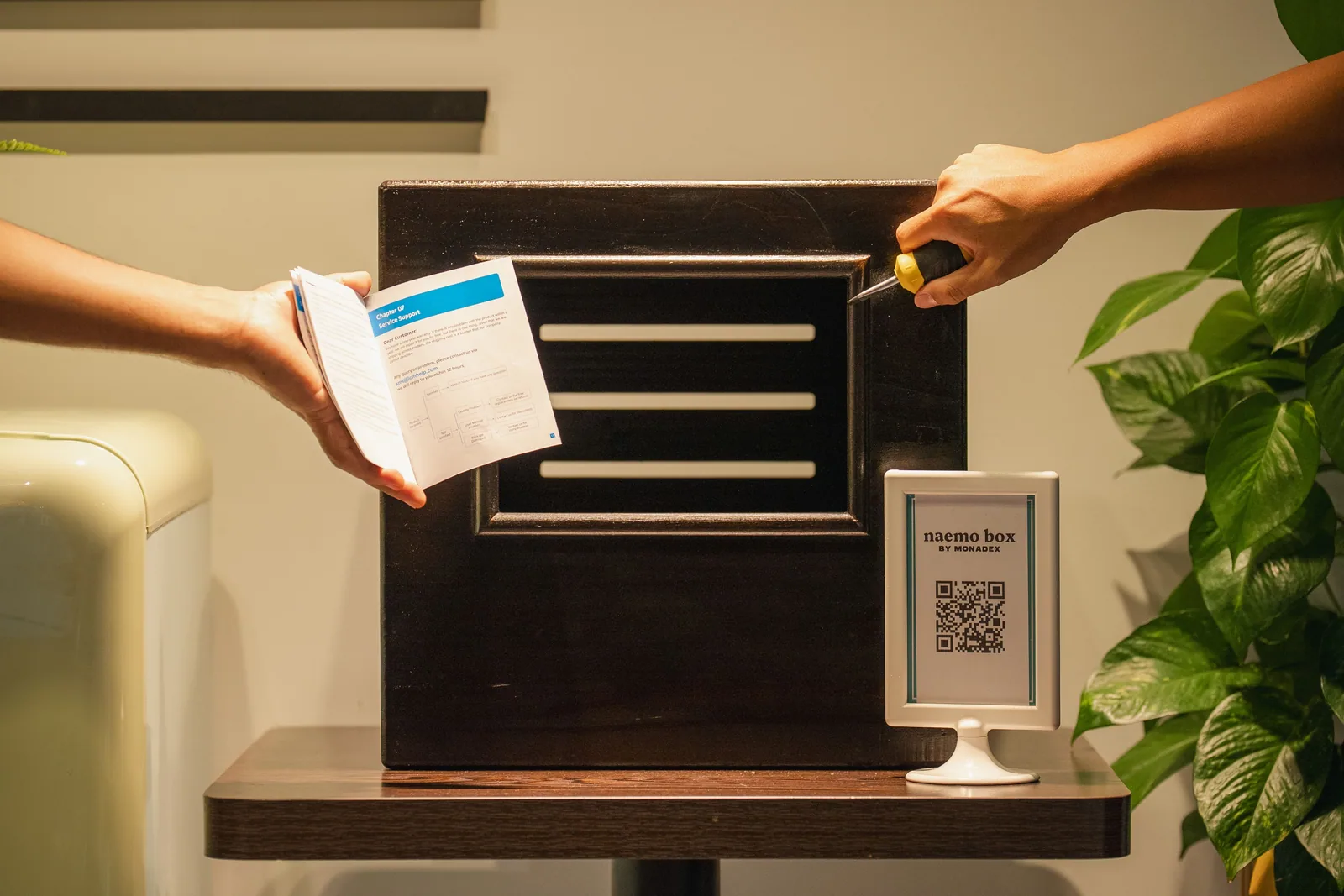 Photo print being handed over at a photo box with a QR sign beside it