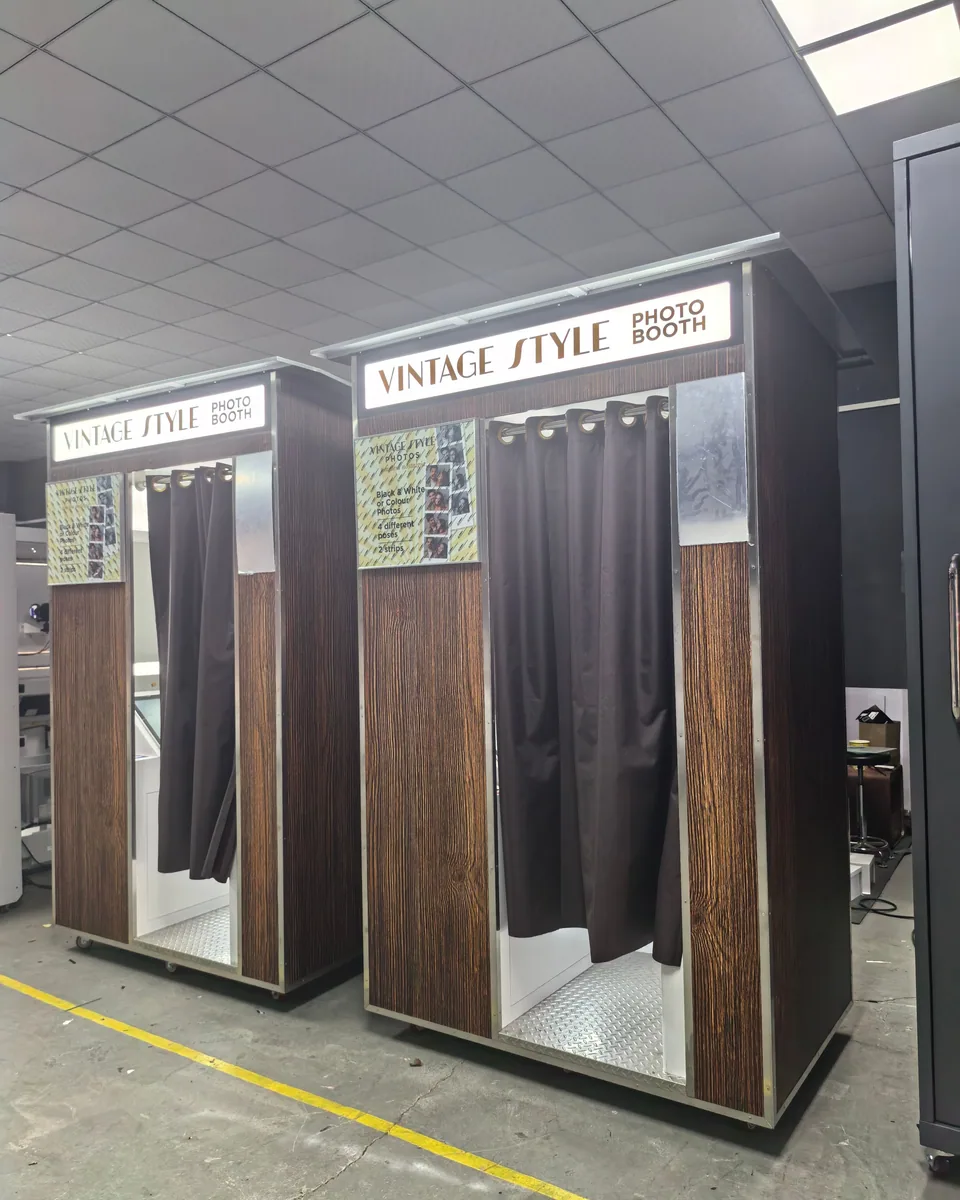 Two vintage-style enclosed photo booths with wood-grain exteriors and curtains